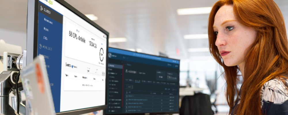 IT-Fachfrau analysiert Daten auf zwei Monitoren mit Cloud- und Systeminformationen im Büro.