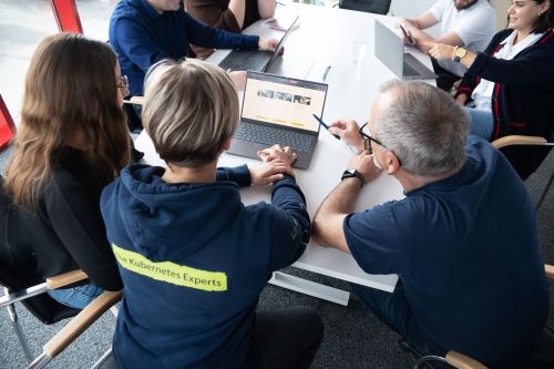 Detailaufnahme einer Besprechung, bei der Personen einen Laptop nutzen uns ich gegenseitig Dinge zeigen.